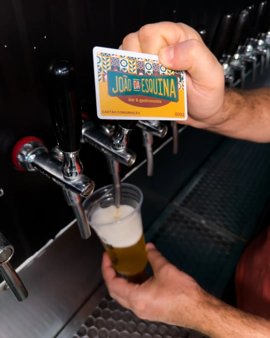 Cliente servindo chope com o cartão de consumo no João da Esquina